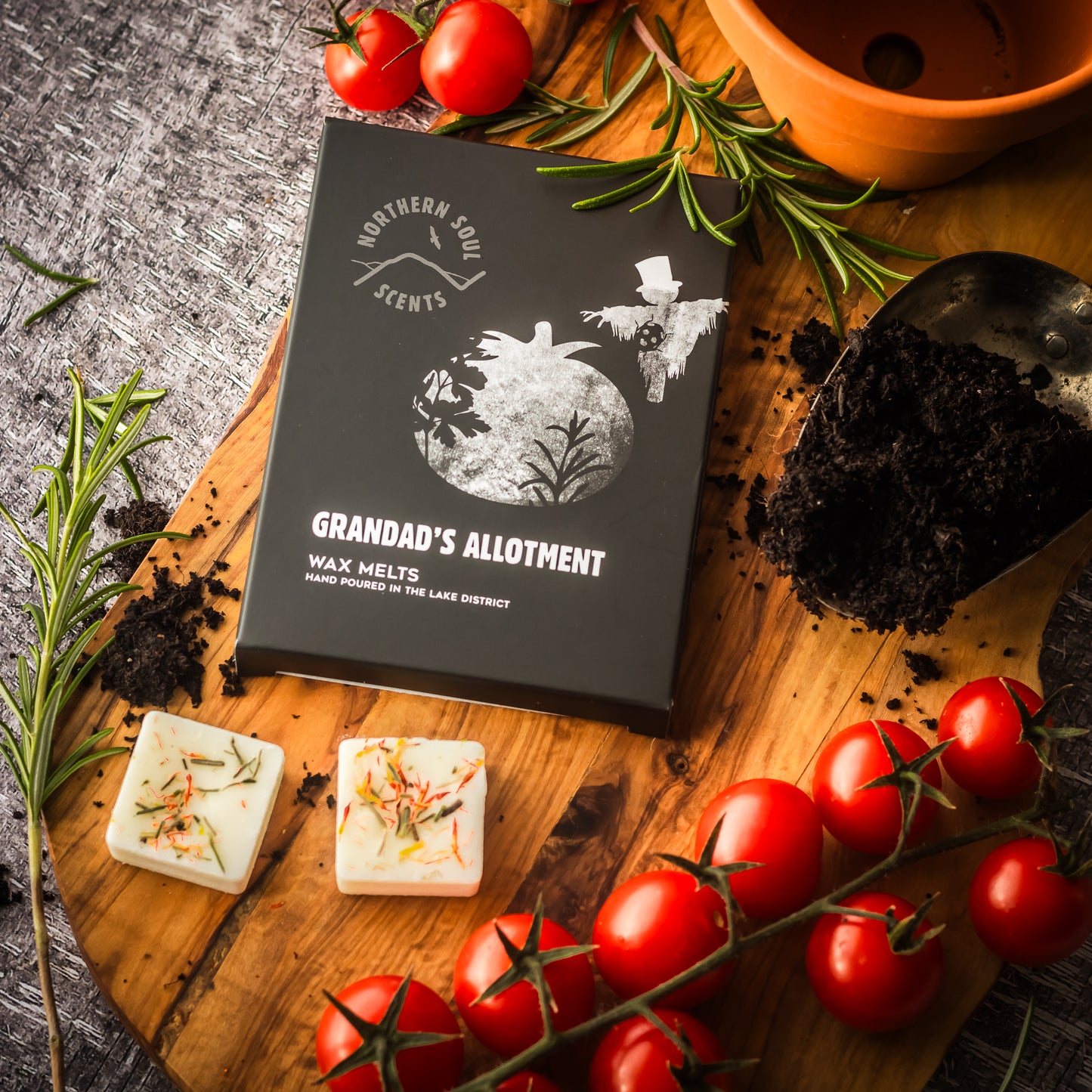 Grandad's Allotment Scented Wax Melts: Delight in the charm of a cherished allotment with these exquisite scented wax melts. Thoughtfully packaged in a plastic-free wax paper bag and enclosed in a cardboard sleeve adorned with a whimsical scarecrow and tomatoes design on the front, these melts evoke the essence of a bountiful garden. Each wax cube is beautifully decorated with dried botanicals, adding a touch of natural allure.