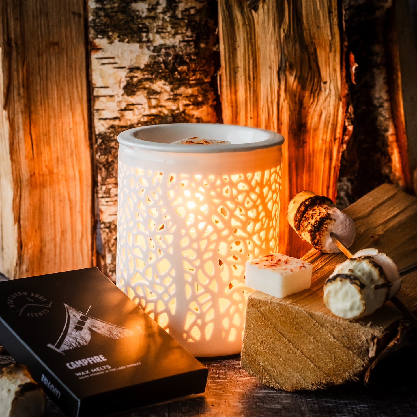 Campfire sweet and smoky scented wax melts shown in an electric wax burner with tree silhouette pattern